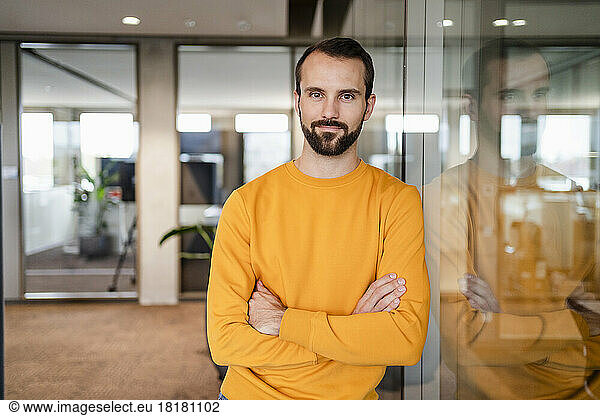 Young businessman with arms crossed at workplace