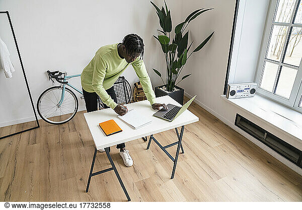 Young businessman writing in note pad at desk