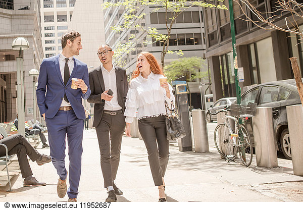 Young businesswoman and businessmen with takeaway coffee strolling along sidewalk  New York  USA
