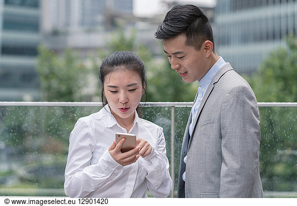Young businesswoman and man looking at smartphone in city  Shanghai  China
