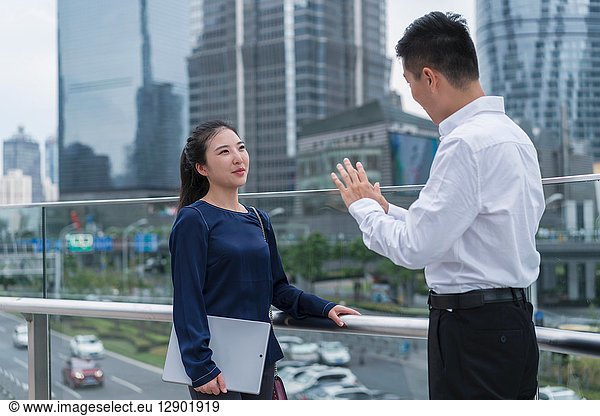 Young businesswoman and man talking on balcony in city financial district  Shanghai  China