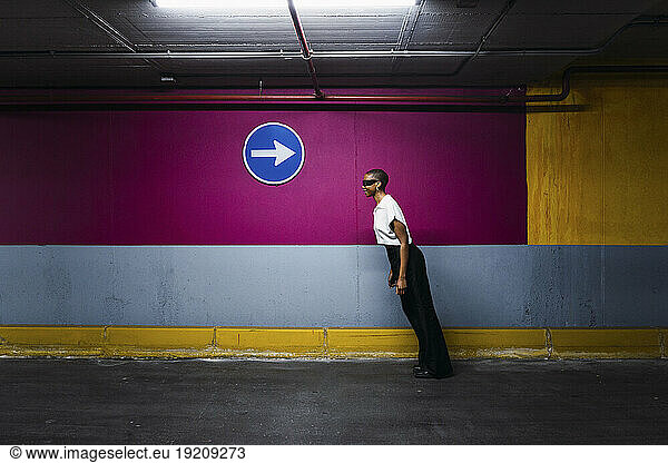 Young businesswoman bending forward in front of wall