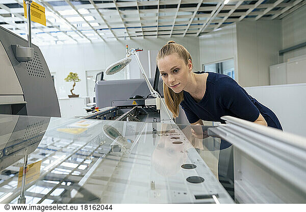 Young businesswoman examining 3D printing machine in industry