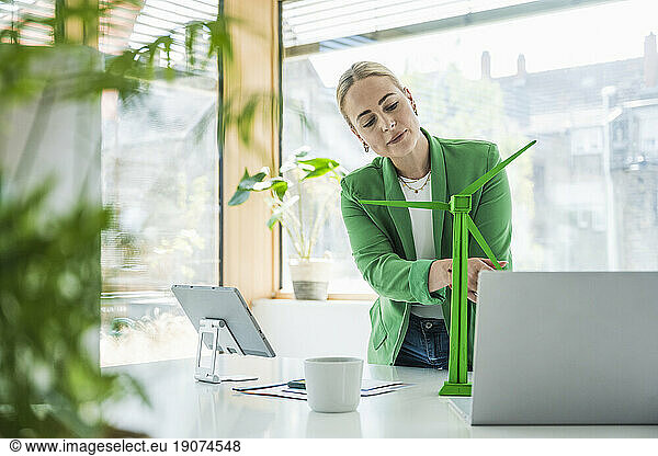 Young businesswoman examining wind turbine model at desk