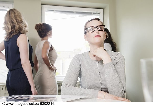 Young businesswoman gazing whilst colleagues look out of window