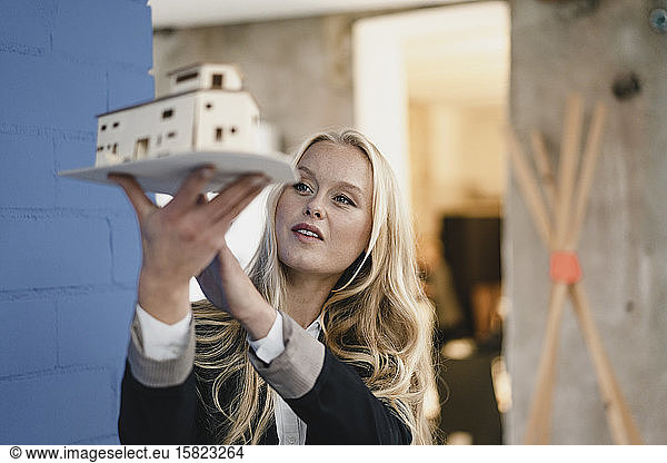 Young businesswoman in loft office holding architectural model