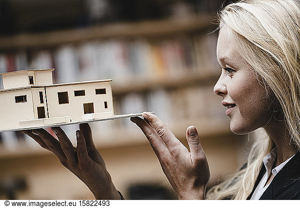 Young businesswoman in office holding architectural model