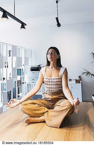 Young businesswoman meditating in office