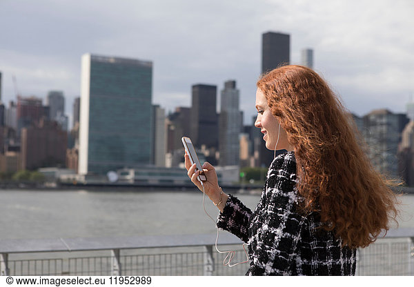 Young businesswoman on waterfront looking at smartphone  New York  USA