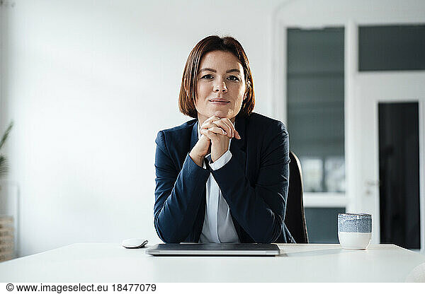 Young businesswoman sitting with laptop and coffee at desk