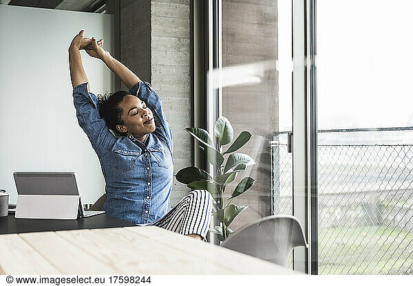 Young businesswoman stretching hands at work place