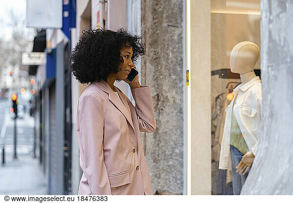 Young businesswoman talking on smart phone and doing window shopping