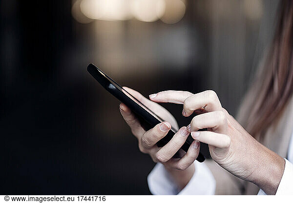 Young businesswoman text messaging through smart phone