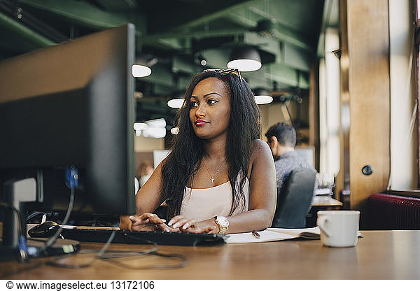Young businesswoman using computer at desk in creative office
