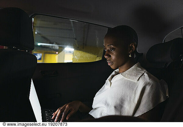 Young businesswoman using laptop in car