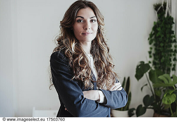 Young businesswoman with arms crossed at office
