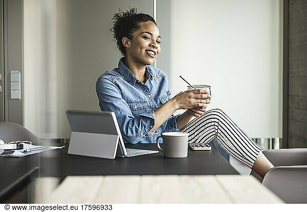 Young businesswoman with food bowl at desk in office