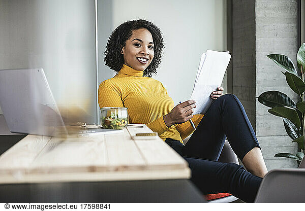 Young businesswoman with paper document at work place
