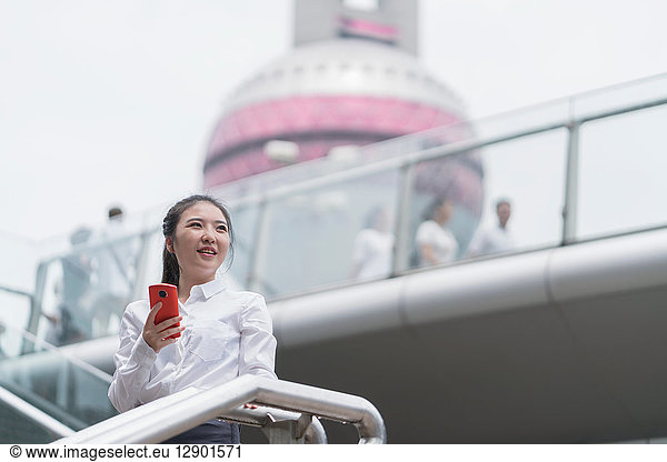 Young businesswoman with smartphone on city stairway  Shanghai  China