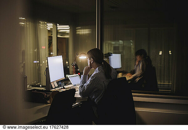 Young businesswoman working on computer late night at work place