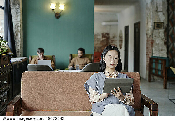 Young businesswoman working on tablet PC in cafe