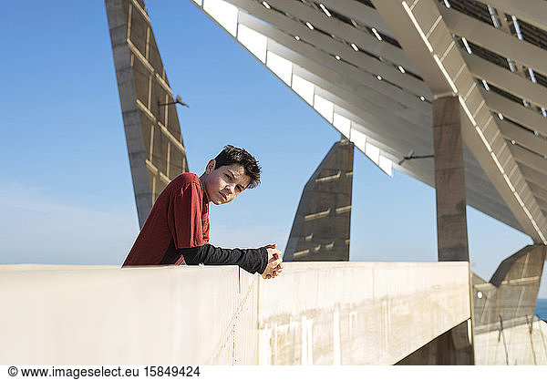 Young cheerful teen leaning on a wall  looking camera in sunny day
