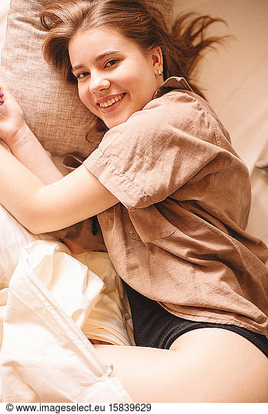 Young cheerful woman lying in bed at home