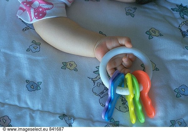 Young child asleep on the bed holding toy keys