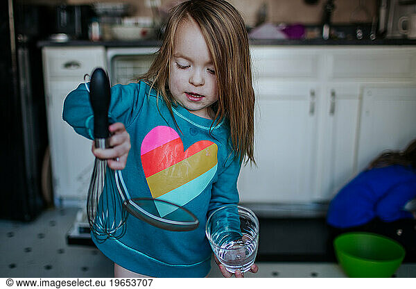 Young child holding clean dishes in kitchen