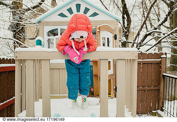 Young child playing in play house in snow storm