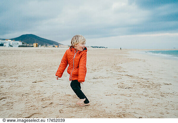 Young child running away from waves at Fuerteventura beach in winter
