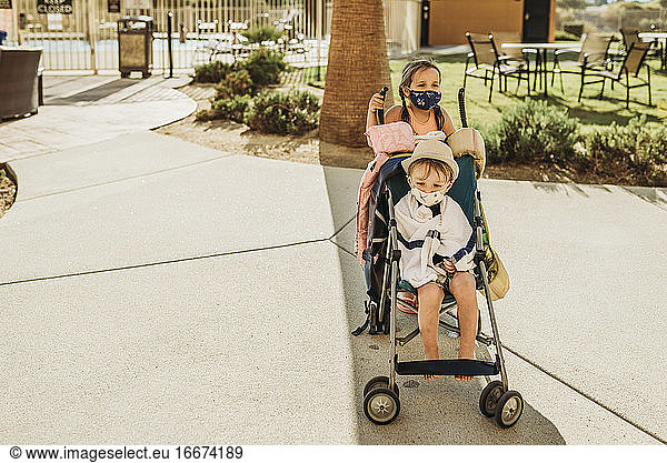 Young children in stroller leaving pool with masks on vacation