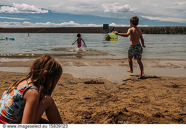 young children playing in sand at a lake in summer