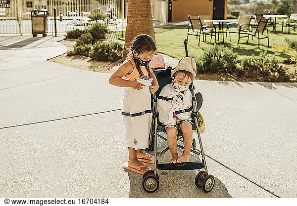 Young children with stroller leaving pool with masks on vacation