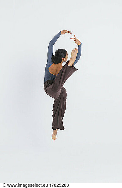 Young classic ballet dancer dancing against white background
