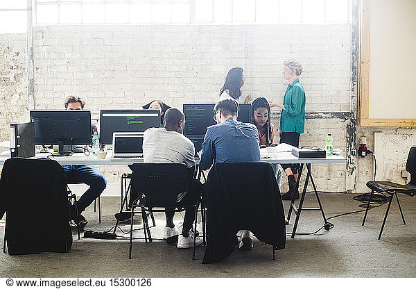 Young computer programmers coding at desk in creative office