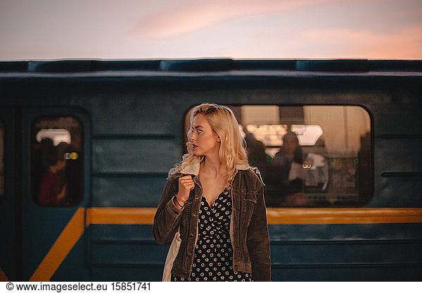 Young confident businesswoman standing against train at subway station