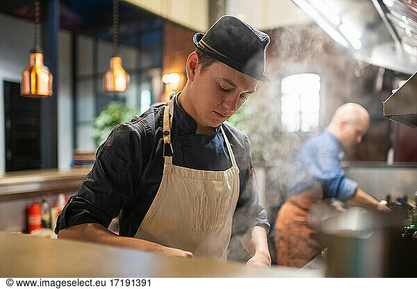 Young cook working in cafe kitchen