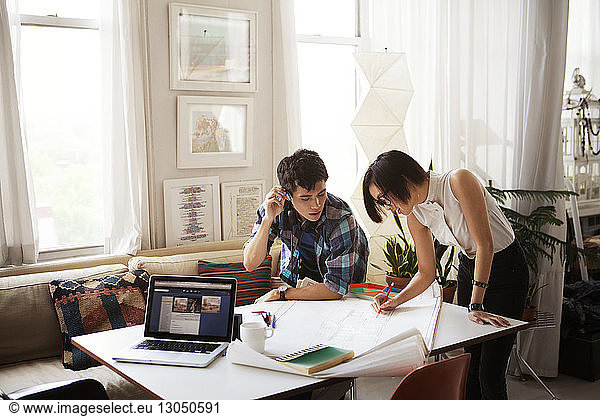 Young couple analyzing blueprint at home
