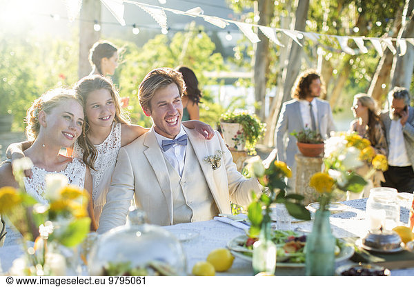 Young couple and bridesmaid during wedding reception in domestic garden