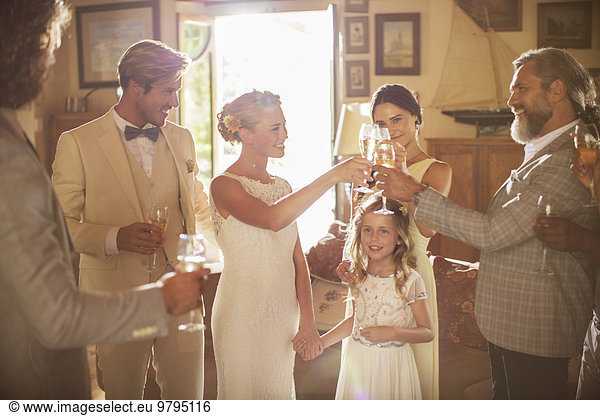 Young couple and guests toasting with champagne during wedding reception in domestic room