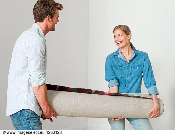 Young couple carrying a rolled up rug
