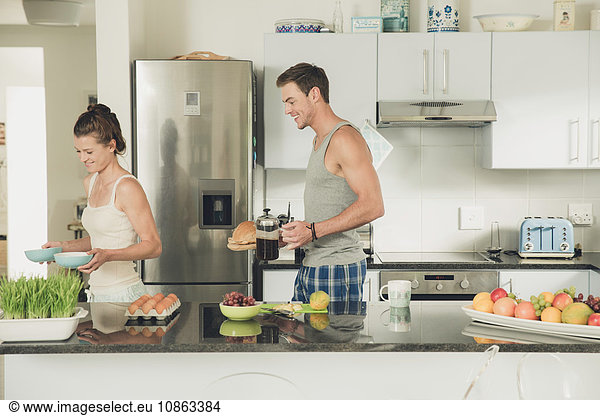 Young couple carrying breakfast from kitchen counter