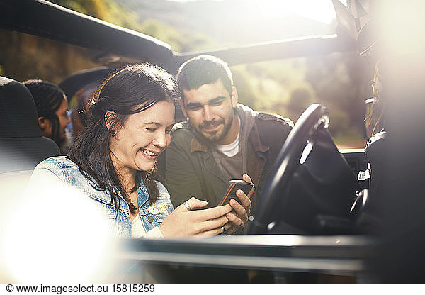 Young couple checking GPS on smart phone  enjoying road trip in jeep