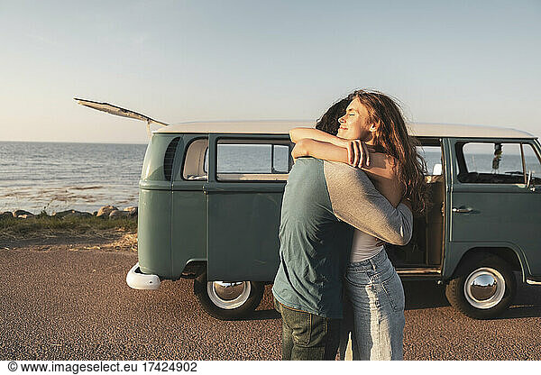 Young couple embracing by sea on road