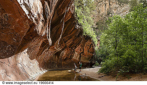 Young couple enjoying a stream under rock ledge