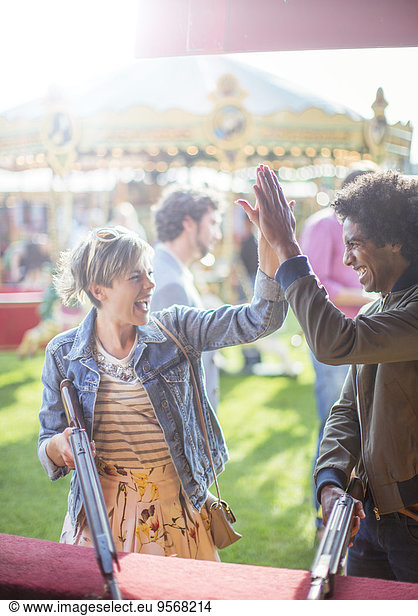 Young couple giving high five in amusement park