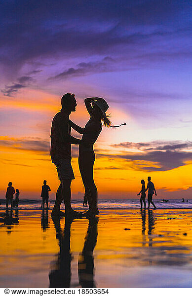 Young couple having fun on the ocean beach. Sunset in Bali.
