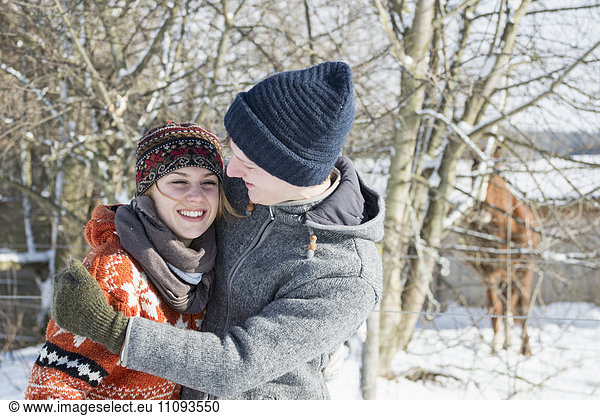 Young couple hugging each other in snow covered landscape  Bavaria  Germany