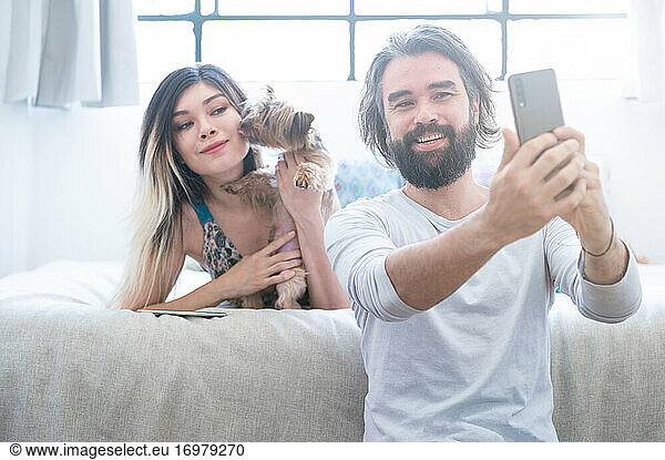 Young couple in love laughing room taking a funny selfie.